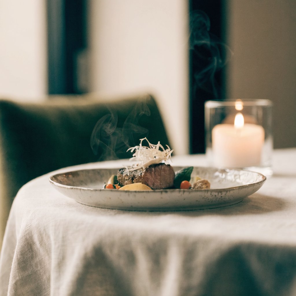 A plated private chef dish, steaming, candlelit